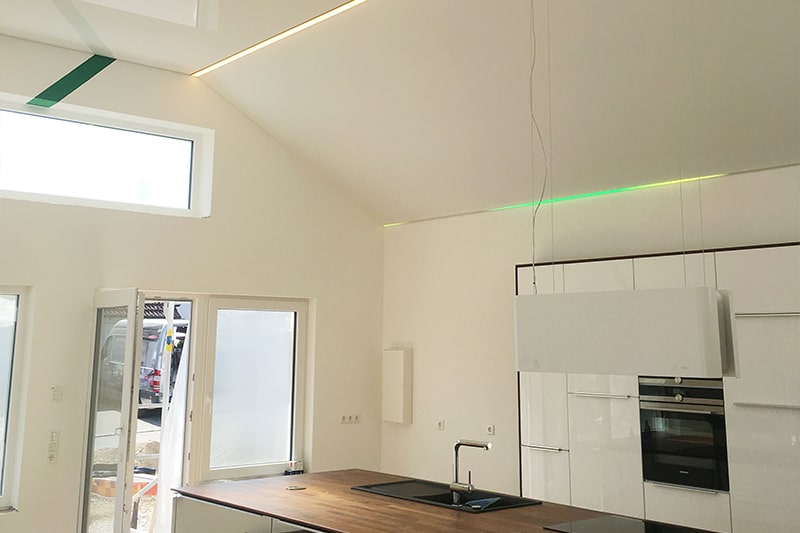 Galerie Spanndecke Küche weiss glanz getrennt mit einer Lichtschiene mit RGB Technik als Trennung zwischen Waagerechter und Dachschräge